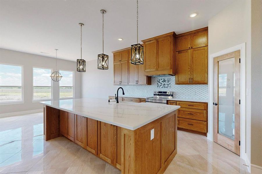 Kitchen featuring light stone counters, decorative light fixtures, light tile patterned floors, an island with sink, and electric range