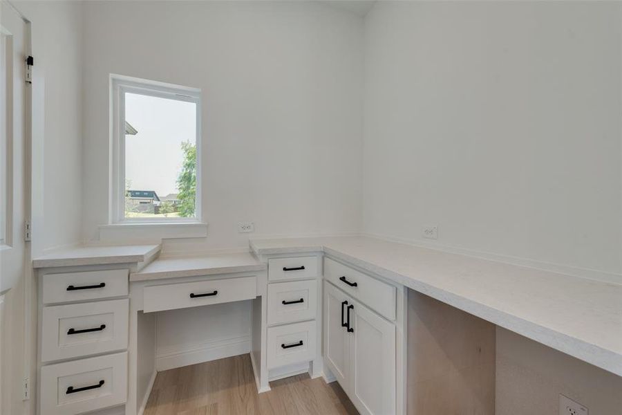 Home office with light hardwood / wood-style floors and built in desk