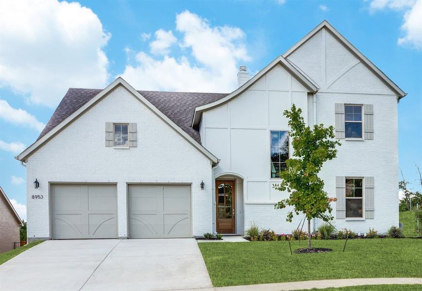 View of front facade featuring a front lawn and a garage