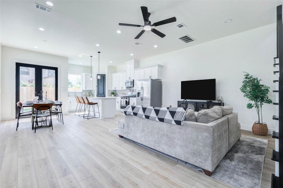 An open-concept layout seamlessly connects the spacious living area to the kitchen, featuring recessed lighting and durable wood-look flooring.