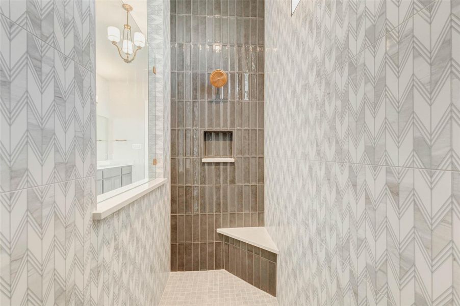 Modern shower with elegant tile work and a sleek built-in bench. The neutral color scheme and stylish fixtures create a luxurious and inviting atmosphere.