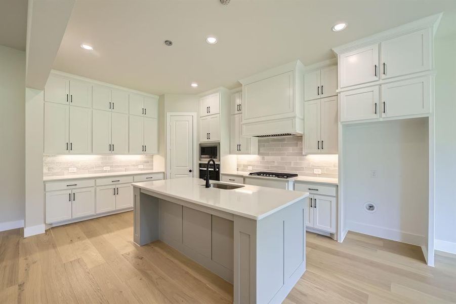 Kitchen featuring appliances with stainless steel finishes, tasteful backsplash, light wood finished floors, white cabinets, and recessed lighting Kitchen featuring appliances with stainless steel finishes, tasteful backsplash, light wood finished floors, white cabinets, and recessed lighting