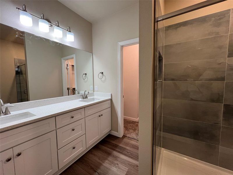 Bathroom featuring wood-type flooring, vanity, and an enclosed shower