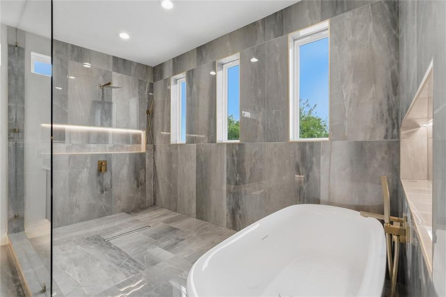 Contemporary bathroom featuring a freestanding soaking tub, a frameless glass shower enclosure, and a built-in shower niche with accent lighting Contemporary bathroom featuring a freestanding soaking tub, a frameless glass shower enclosure, and a built-in shower niche with accent lighting