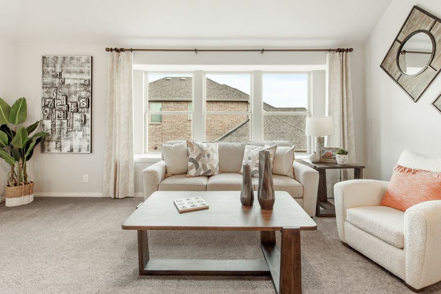 Living room with beige sofa, wood coffee table, carpet flooring, and large bay window with curtains