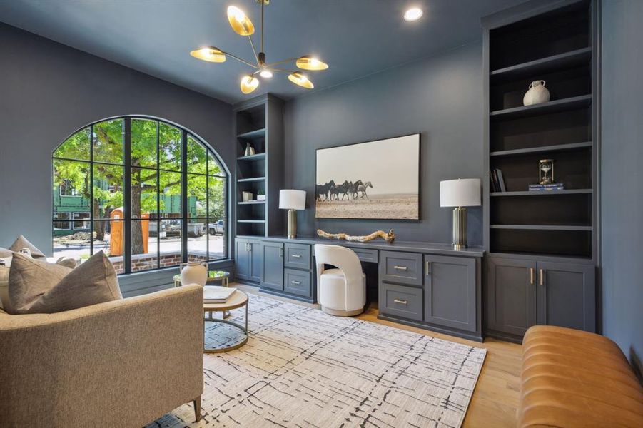 Living room with light hardwood,  built in desk, a notable chandelier, and built in features