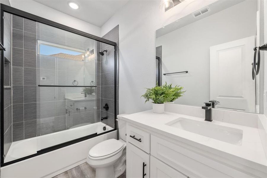 Full bathroom with wood-type flooring, toilet, combined bath / shower with glass door, and vanity