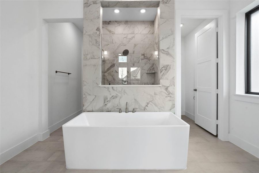 The centerpiece of this contemporary primary bath is the deep, freestanding bathtub, offering an ideal spot for relaxation with a unique view into the walk-in shower.