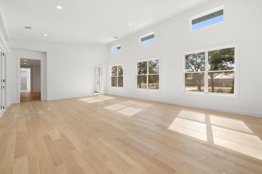 Unfurnished living room with a high ceiling, light wood finished floors, and recessed lighting