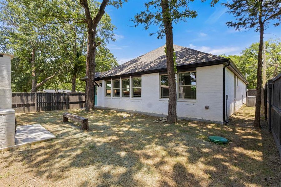 Back of house with roof with shingles, a fenced backyard, and brick siding Back of house with roof with shingles, a fenced backyard, and brick siding