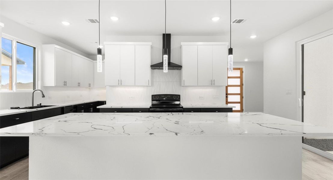 Kitchen featuring white cabinetry, light wood finished floors, a kitchen island, light stone counters, and recessed lighting