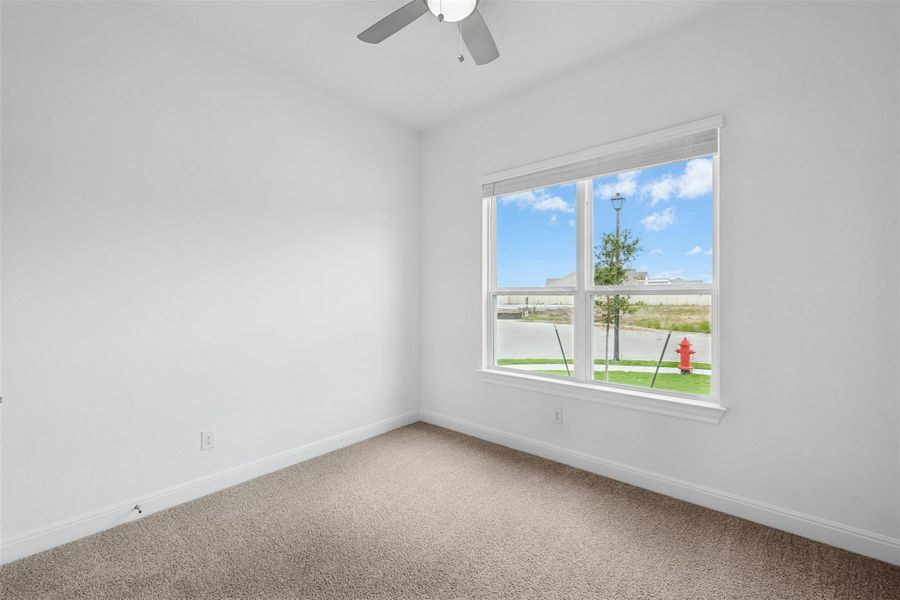 A well-lit room offers ample natural light and a practical ceiling fan.