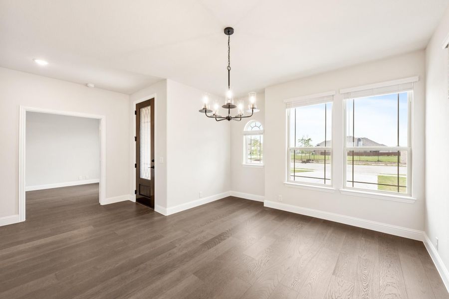 Empty dining room with dark hardwood floors, chandelier, and large windows with outdoor views