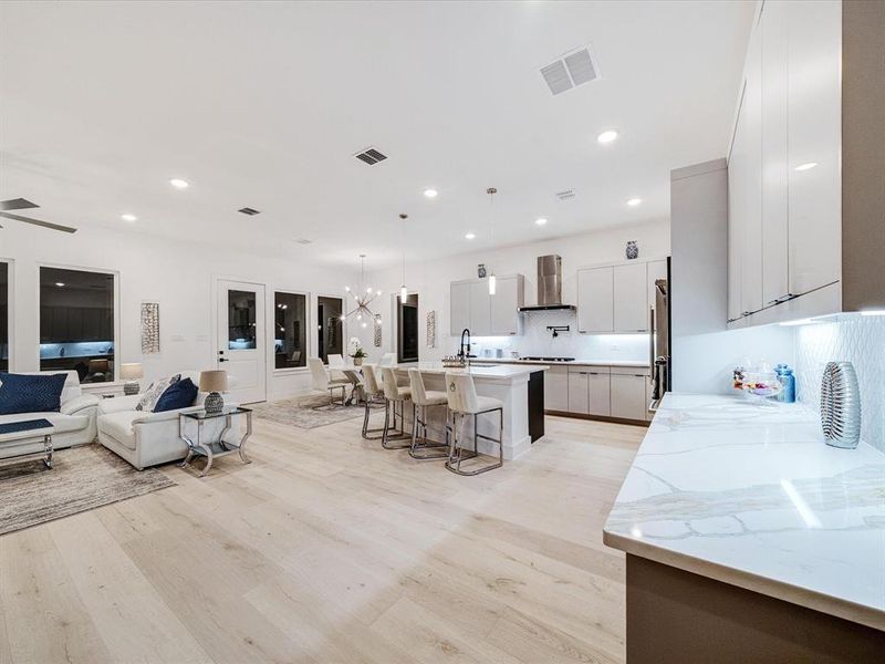 Kitchen featuring a breakfast bar, a chandelier, open floor plan, a kitchen island with sink, and hanging light fixtures Kitchen featuring a breakfast bar, a chandelier, open floor plan, a kitchen island with sink, and hanging light fixtures