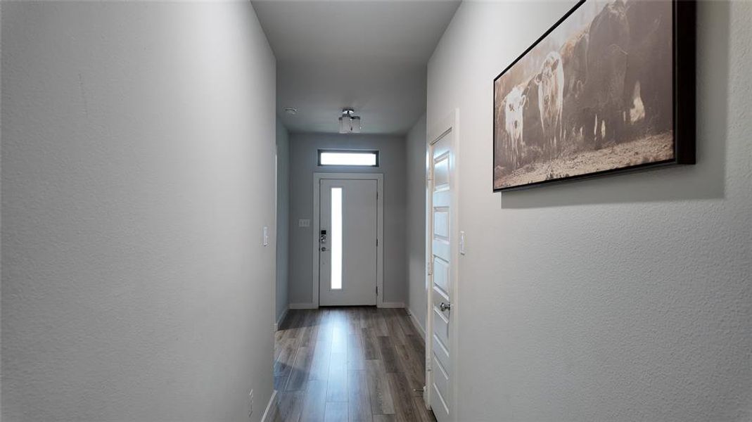 The property features a bright entryway with light wood-look flooring and a modern white front door, complemented by light grey walls