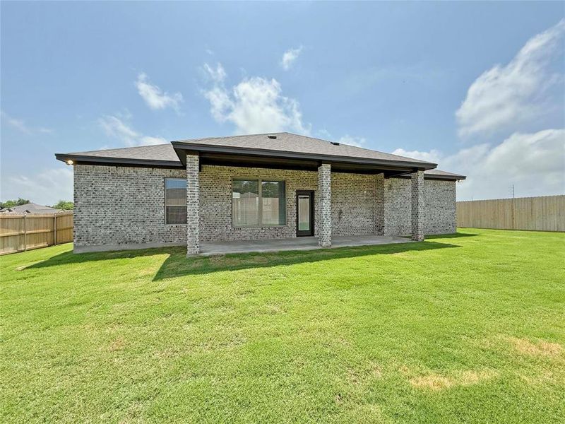 Rear view of house with a patio, a yard, brick siding, and fence Rear view of house with a patio, a yard, brick siding, and fence