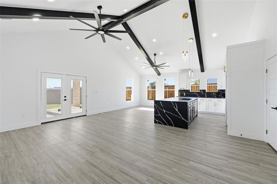 Living room featuring high vaulted ceiling, beam ceiling, french doors, light wood-style flooring, and recessed lighting Living room featuring high vaulted ceiling, beam ceiling, french doors, light wood-style flooring, and recessed lighting