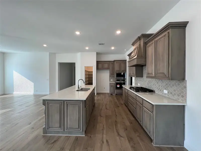 Kitchen with quartz countertops, Charleston cabinetry, Arabesque tile backsplash, dark wood-type flooring, recessed lighting, built-in oven/microwave combination, and an island with dual sink Kitchen with quartz countertops, Charleston cabinetry, Arabesque tile backsplash, dark wood-type flooring, recessed lighting, built-in oven/microwave combination, and an island with dual sink