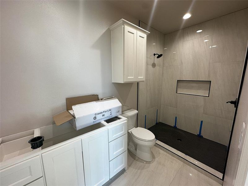 Bathroom featuring tiled shower, toilet, and sink