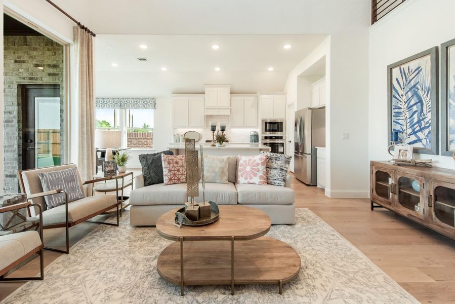 Open-concept living room with hardwood floors, gray sofa, and kitchen visible in background Open-concept living room with hardwood floors, gray sofa, and kitchen visible in background