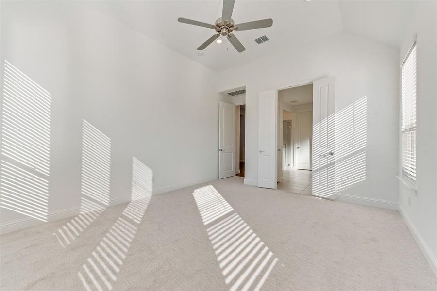 Carpeted empty room featuring high vaulted ceiling and ceiling fan