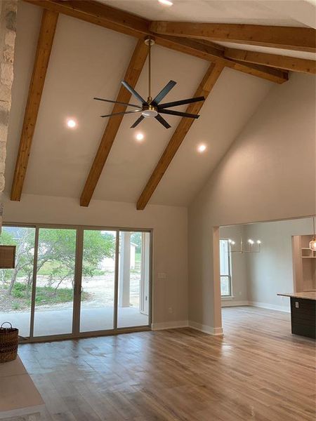 Living room with vaulted beamed ceiling and extra large ceiling fan with remote, recessed lights, open to kitchen