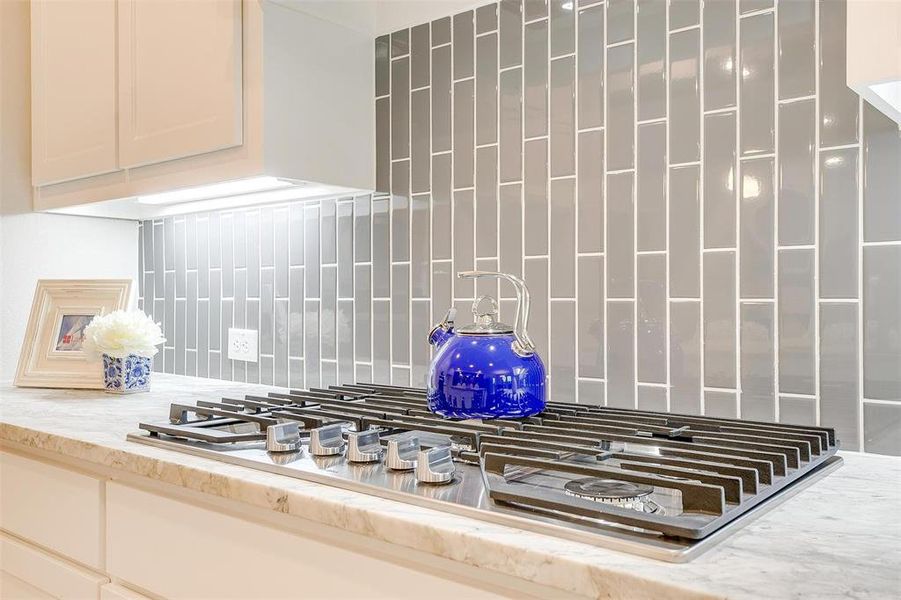 Room details featuring stainless steel gas stovetop and decorative backsplash