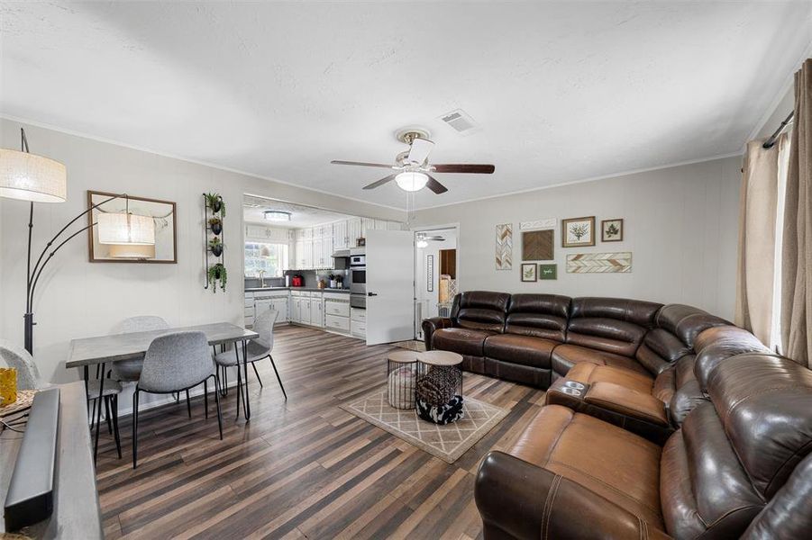 Living room featuring dark wood finished floors, crown molding, and ceiling fan Living room featuring dark wood finished floors, crown molding, and ceiling fan