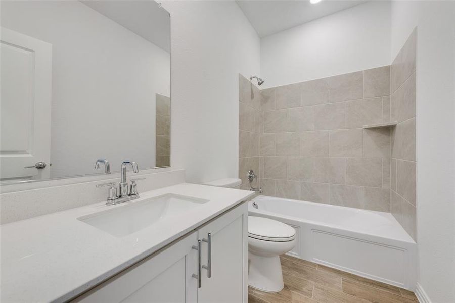 Full bathroom featuring tiled shower / bath, vanity, and toilet