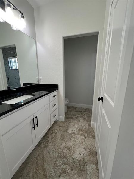 Bathroom with baseboards, toilet, vanity, and walk in shower