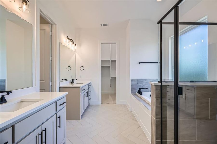 Bathroom featuring two vanities, a bath, a shower stall, and baseboards Bathroom featuring two vanities, a bath, a shower stall, and baseboards
