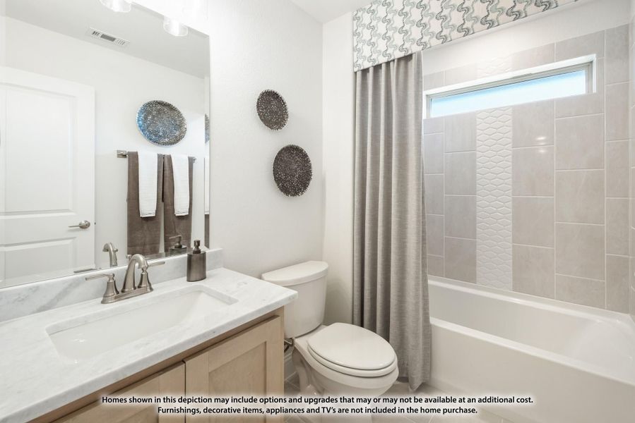 Bathroom with marble countertop vanity, toilet, and tub-shower combo with gray tile surround and curtain Bathroom with marble countertop vanity, toilet, and tub-shower combo with gray tile surround and curtain