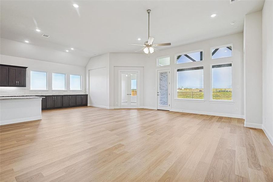 Unfurnished living room featuring light wood-style floors, ceiling fan, recessed lighting, and vaulted ceiling