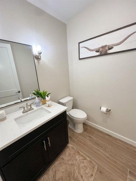 Half bath featuring vanity, wood finish floors, and a textured wall