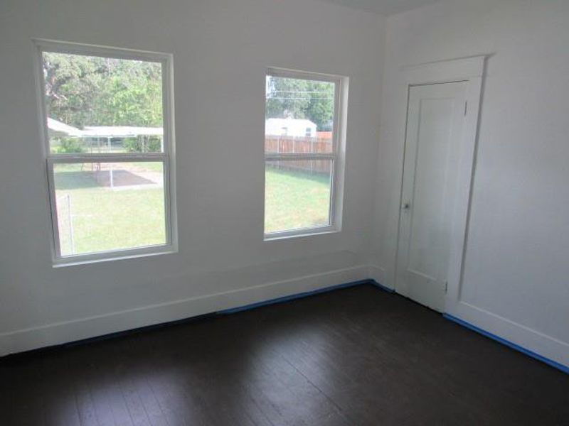 Empty room with dark wood-type flooring and baseboards Empty room with dark wood-type flooring and baseboards
