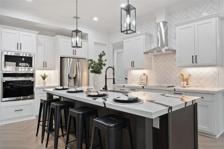 Kitchen with stainless steel appliances, a breakfast bar area, crown molding, light stone countertops, and hanging light fixtures
