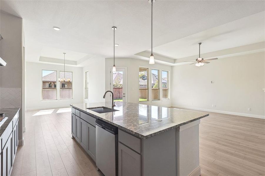 Kitchen with an island with sink, light hardwood / wood-style flooring, gray cabinetry, sink, and stainless steel dishwasher