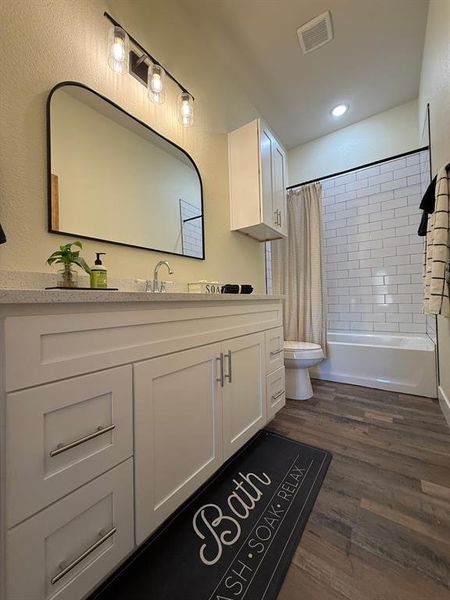 Hallway bathroom and white subway tile and custom mirror.  White quart countertops and designer lightning.