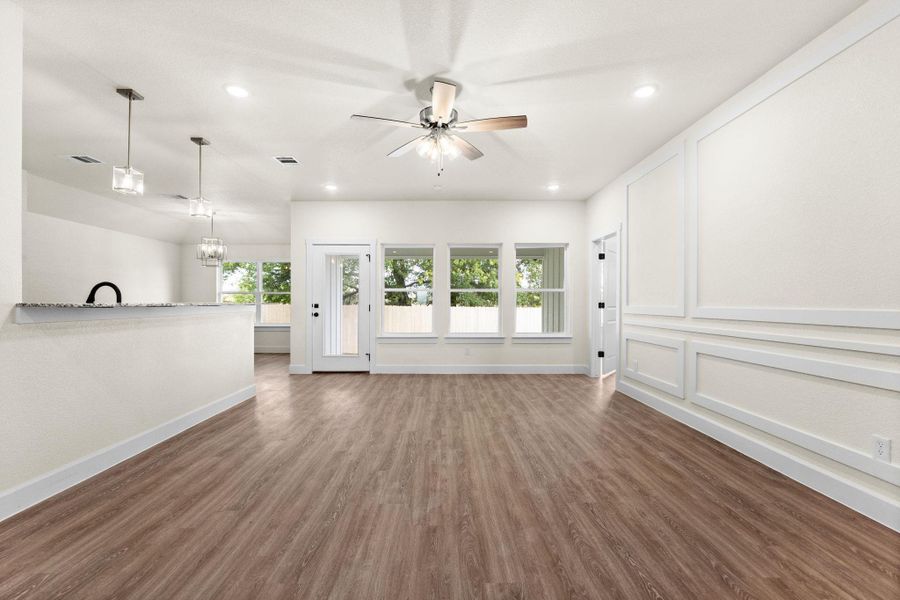 Unfurnished living room featuring dark wood finished floors, a decorative wall, a chandelier, recessed lighting, and ceiling fan