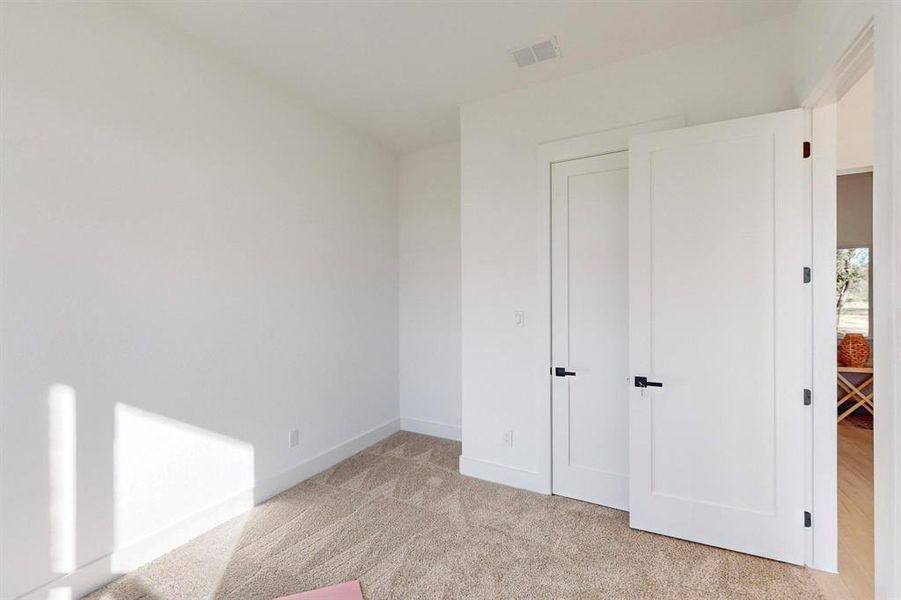 Unfurnished bedroom with baseboards, visible vents, and light colored carpet