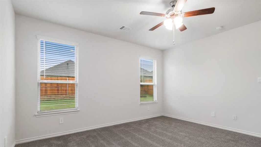 Unfurnished room with dark colored carpet and a ceiling fan