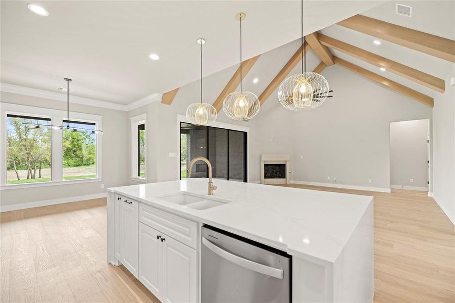 Kitchen with a chandelier, decorative light fixtures, light stone countertops, white cabinets, and a center island with sink Kitchen with a chandelier, decorative light fixtures, light stone countertops, white cabinets, and a center island with sink