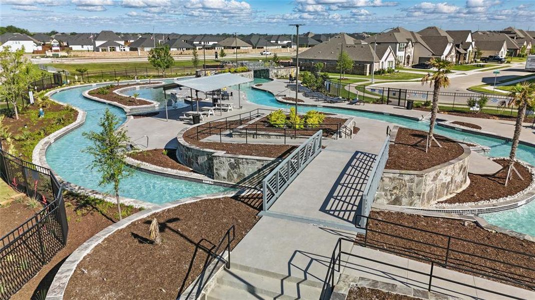 Winding lazy river with bridges, surrounding landscaped areas, and nearby residential properties Winding lazy river with bridges, surrounding landscaped areas, and nearby residential properties