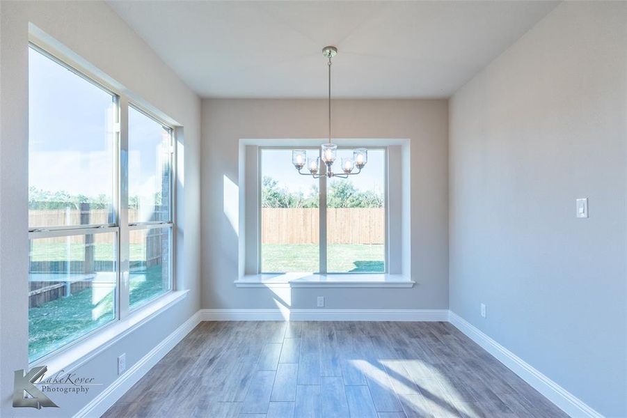 Unfurnished dining area featuring wood finished floors and a chandelier