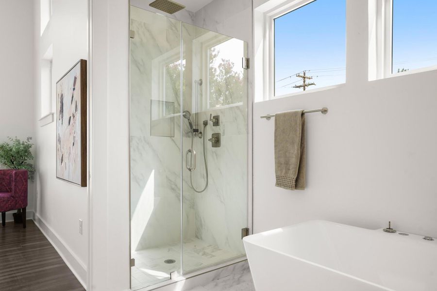 A well-lit primary bathroom featuring a spacious glass-enclosed shower and a standalone tub. A well-lit primary bathroom featuring a spacious glass-enclosed shower and a standalone tub.