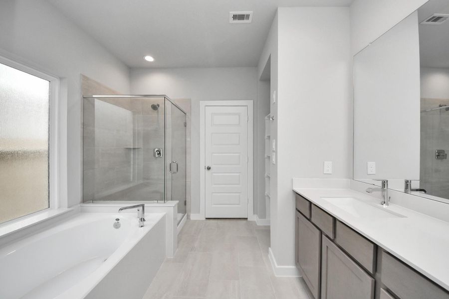 Escape to a spa-like oasis in this primary bathroom. Enjoy a walk-in shower with tile surround, a separate garden tub with custom detailing, and an elegant vanity featuring light countertops, modern hardware, and beautiful recessed lights. Experience luxury and relaxation in every detail.