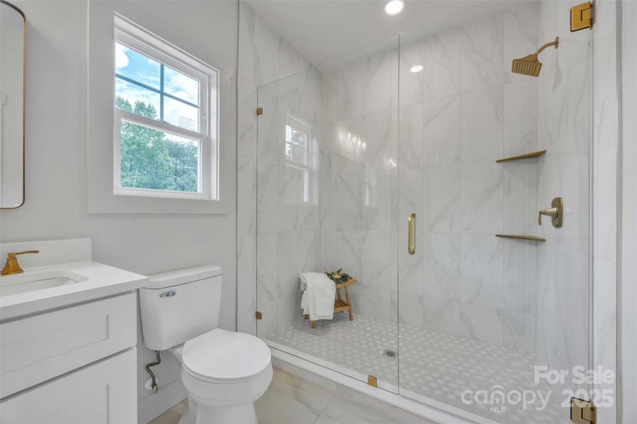 Floor to ceiling tiled shower w/gold hardware