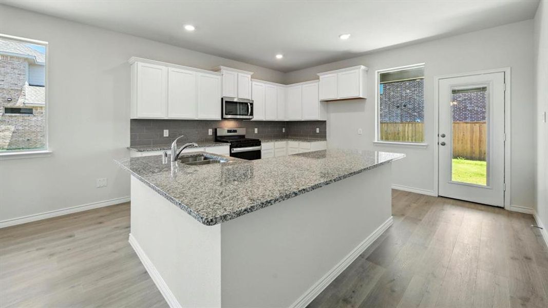 Kitchen with light stone countertops, white cabinetry, healthy amount of natural light, appliances with stainless steel finishes, and recessed lighting