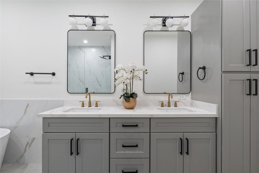 The primary ensuite features dual vanities with ample storage, including generous cabinetry for all your essentials. Elegant gold fixtures add a touch of luxury and sophistication. This combination of style and functionality makes daily routines effortless and refined.
