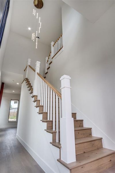 Staircase with wood finished floors, a towering ceiling, and recessed lighting Staircase with wood finished floors, a towering ceiling, and recessed lighting
